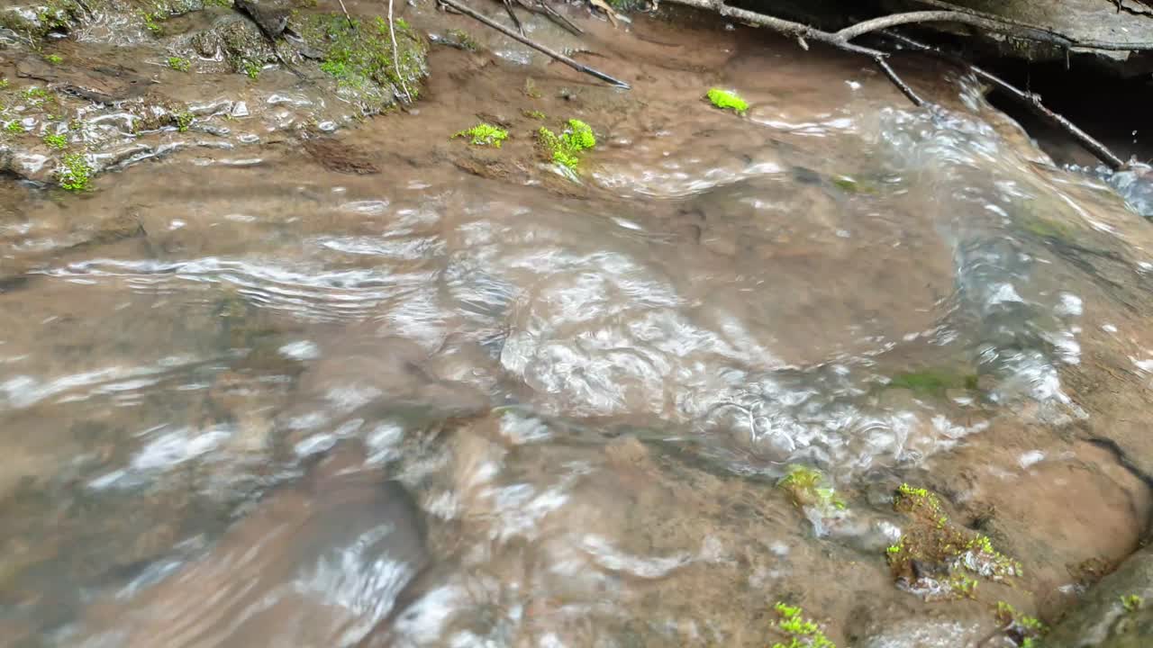 meditate tranquil and peaceful calm slow motion footage of flowing water from a mountain spring water stream running down huge sandstone slabs of rock with green moss, crystal clear drinking water