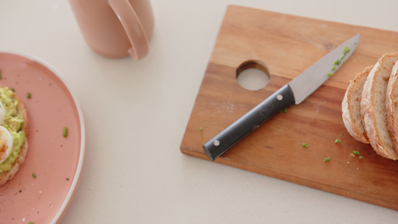 Eating avocado toast with boiled eggs, asian woman enjoying breakfast at home
