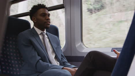 businessman and businesswoman commuting to work talking in train carriage