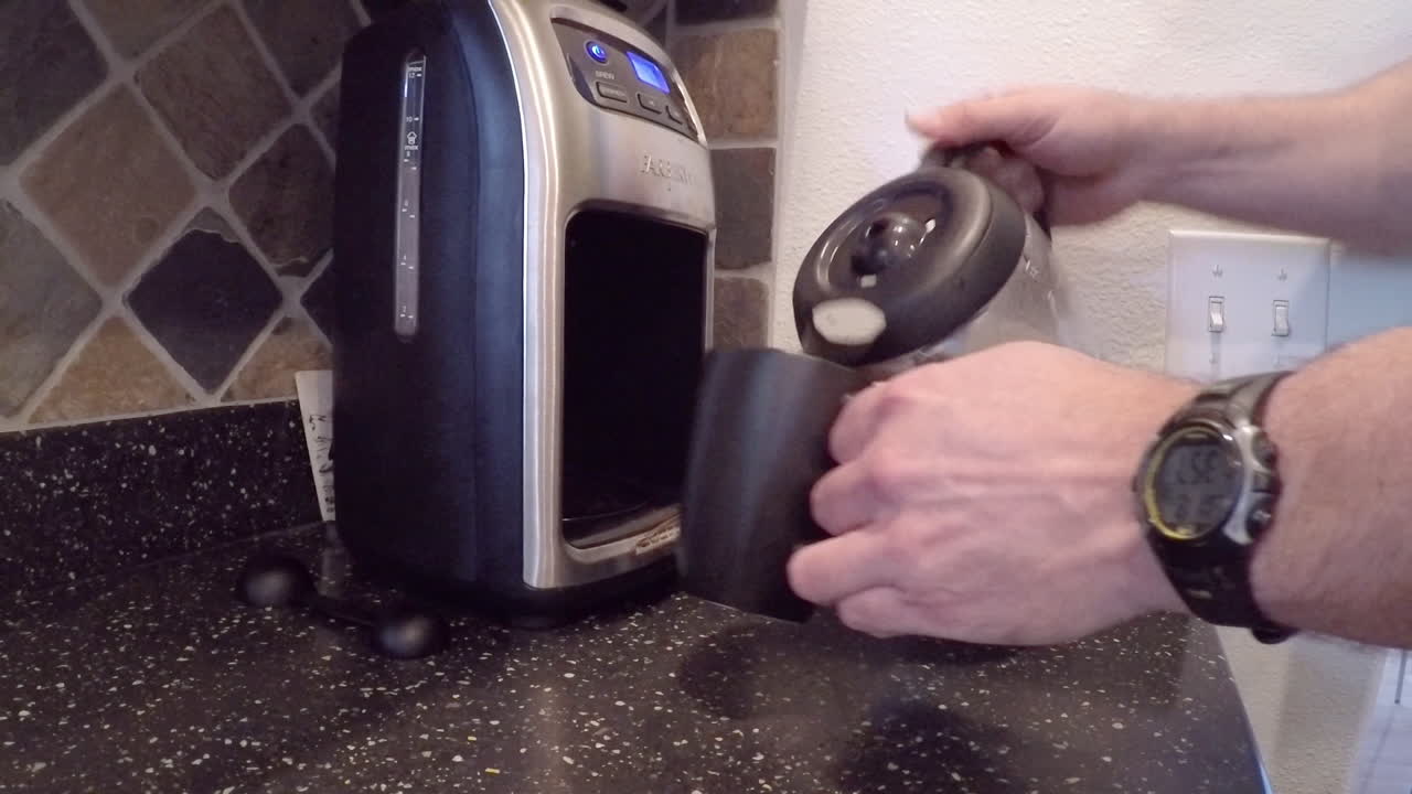 Versare una tazza di caffè fresco mattutino da una macchina da caffè in cucina
