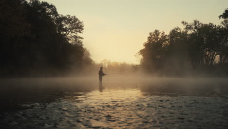 fisherman at sunrise in a misty forest