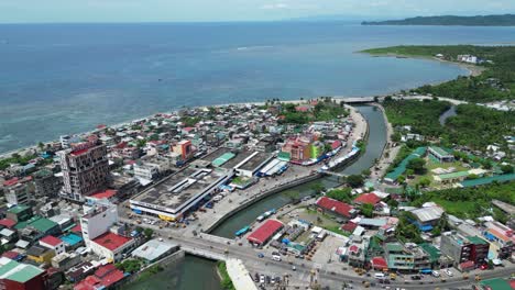 high angle, rising, aerial view of waterfront town of virac, catanduanes, philippines with busy traffic and open sea in background