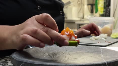 Professional-cooker-presents-ceviche-in-dark-stone-plate