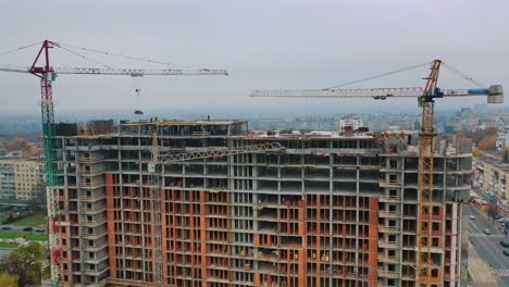 new construction in the city center. wide high-rise building under construction outdoors. aerial view. camera moving around.