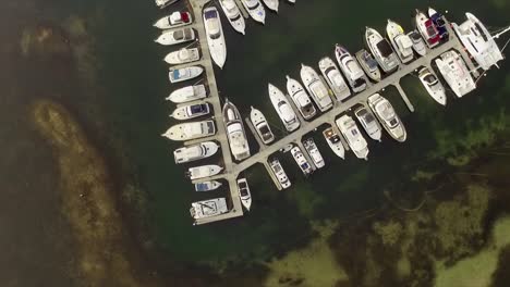 Aerial-drone-shot,-looking-straight-down-on-a-yachts-in-a-small-marina-on-Lake-Macquarie,-Australia
