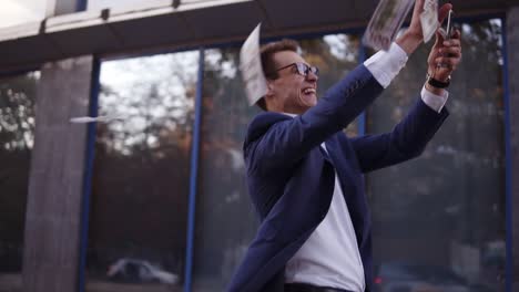 happy young businessman in blue suit walks in excitement and throw handful of banknotes in the air. super excited businessmen in