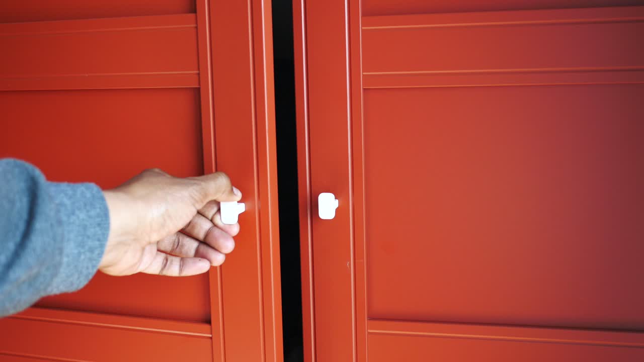 Person opening a red metal garage door