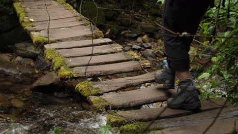 hanging old mossy bridge with river under it tourist walks over in slow motion