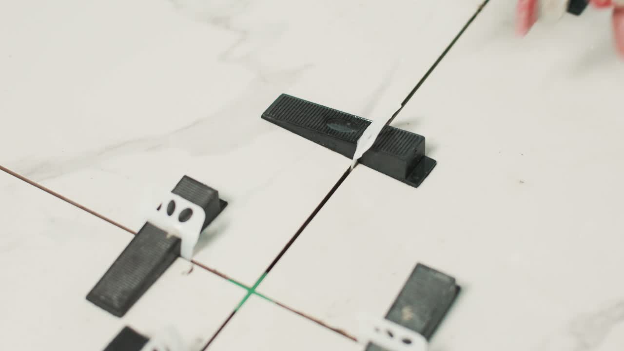 trabajador de la construcción instalando cuñas de plástico en baldosas cerámicas