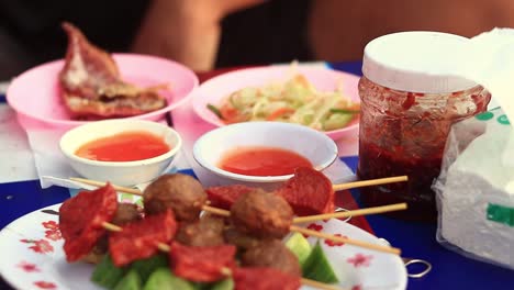 Cerca-De-Un-Plato-Lleno-De-Brochetas-De-Comida-Callejera-Khmer-Fritas-Que-Se-Comen-Por-Un-Turista