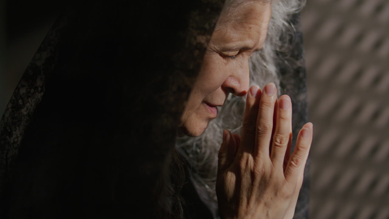 Senior Woman in Black Veil Praying Deeply to God in Confessional Booth