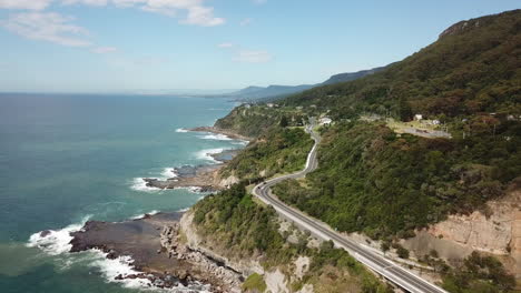 aerial: drone flying lower towards a highway on a beautiful coastline in new south wales australia