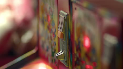 medium closeup of hand inserting coin into carnival game machine at night