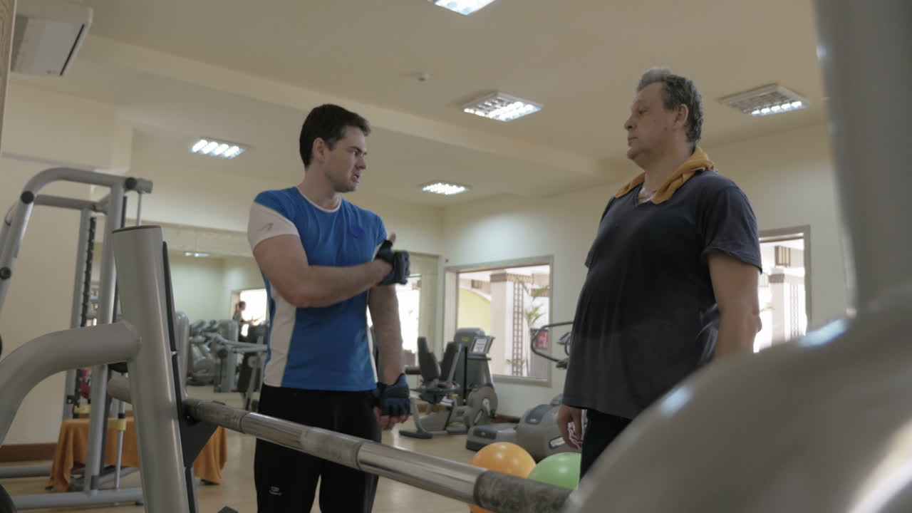 instructor de gimnasio dando consultas a un hombre