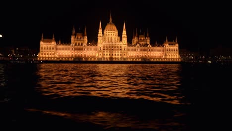 Das-Äußere-Des-Ungarischen-Parlaments-Bei-Nacht-Mit-Dem-Mond-Im-Hintergrund,-Donau,-Budapest
