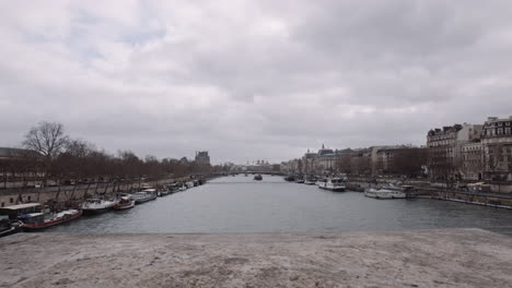 boats moored along the seine river on a cloudy day in paris, france