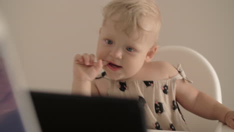 one year child watching cartoons sitting in highchair