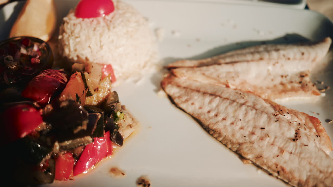 Two beautifully prepared seafood dishes are served on a wooden restaurant table in warm natural sunlight