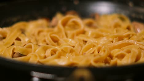 rotating view of italian creamy mushroom tagliatelle pasta resting after cooking in frying pan 4k