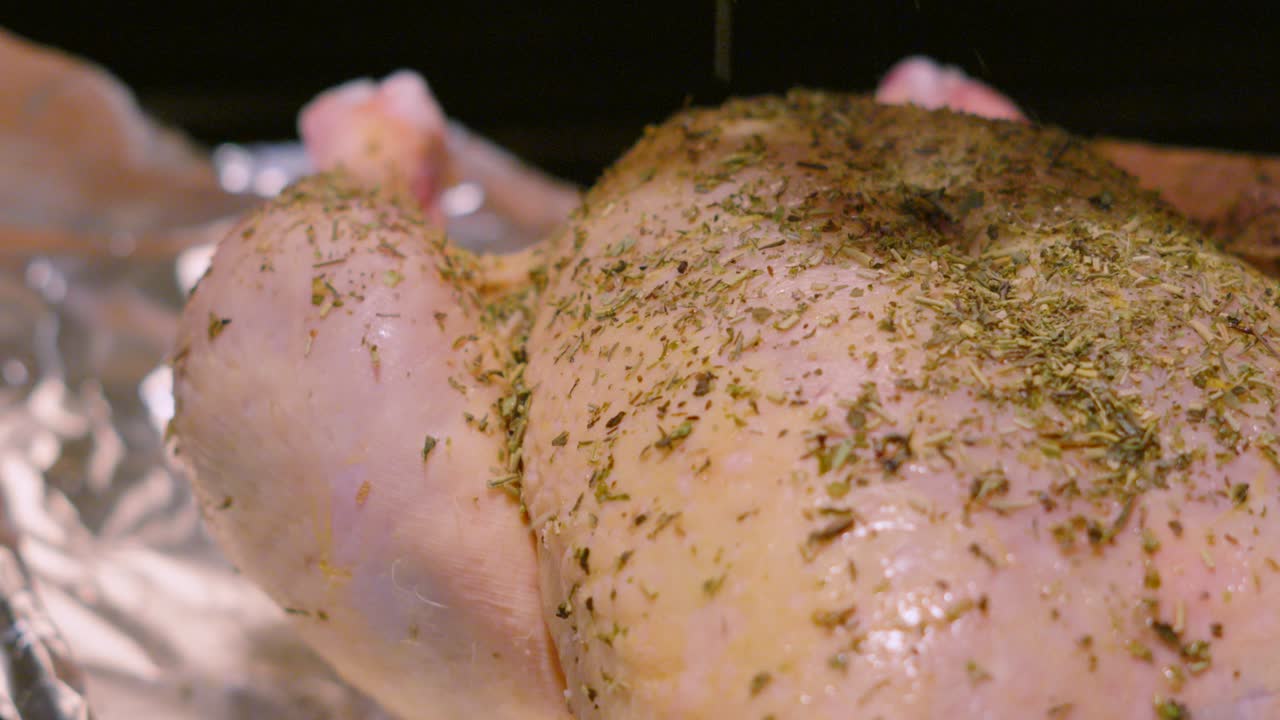 Slow Pushing Shot Towards Raw Whole Free Range Chicken with Seasoning Being Dropped on Top for Extra Flavour in Slow Motion Ready for Roasting in Oven After Preparation. Cooking Food Footage 4K.