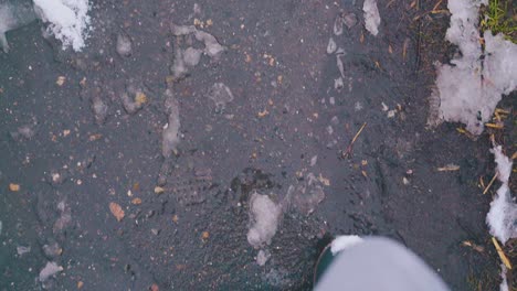 feet in boots walk fast along dark asphalt road with sleek