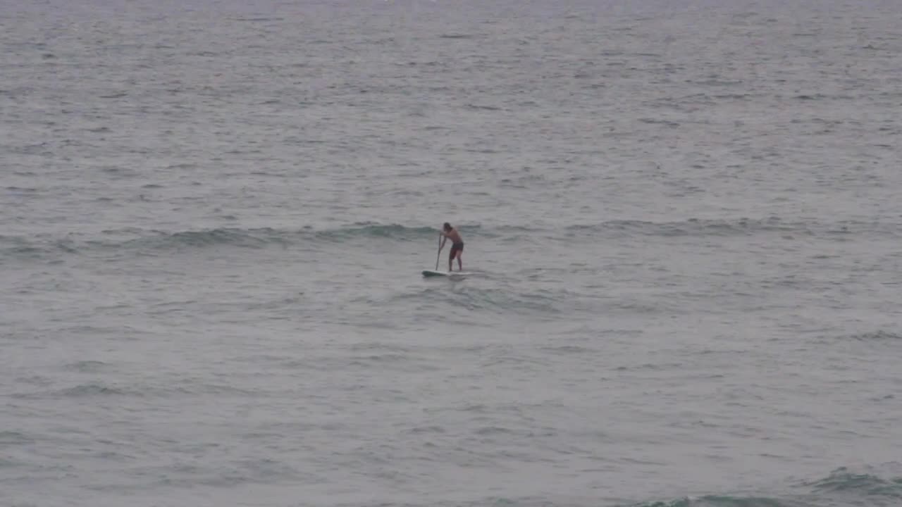 long shot, a man doing stand up paddle in the Caribbean ocean cloudy