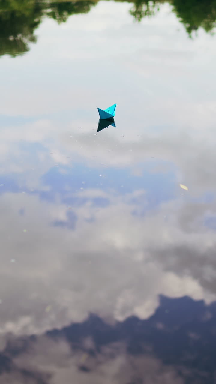 Paper boat on the river. Paper boat sailing along the river. Vertical video