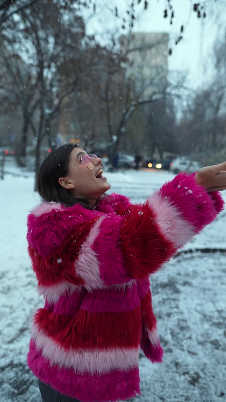분홍색 털 코트 를 입은 여자 가 눈 을 즐기고 있다