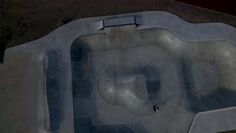 Skateboarder-in-action-at-a-skatepark,-aerial-view-capturing-the-vast-layout---top-down-aerial-shot