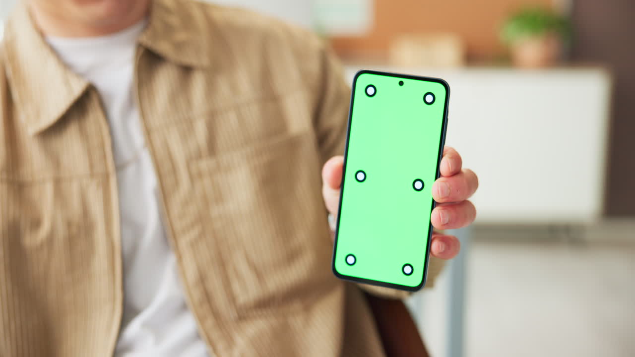 Uomo che tiene in mano uno smartphone con schermo verde