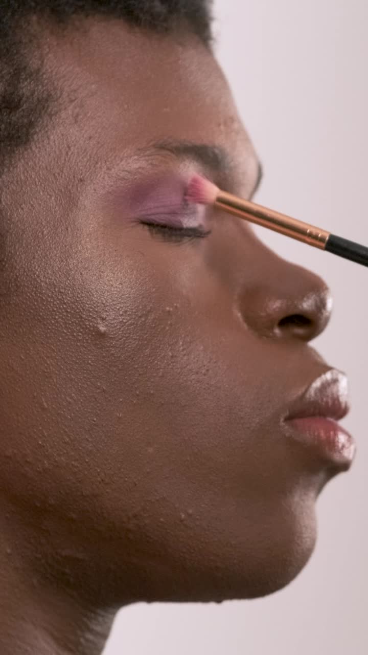 Crop visagiste filling in eyebrows of black transgender