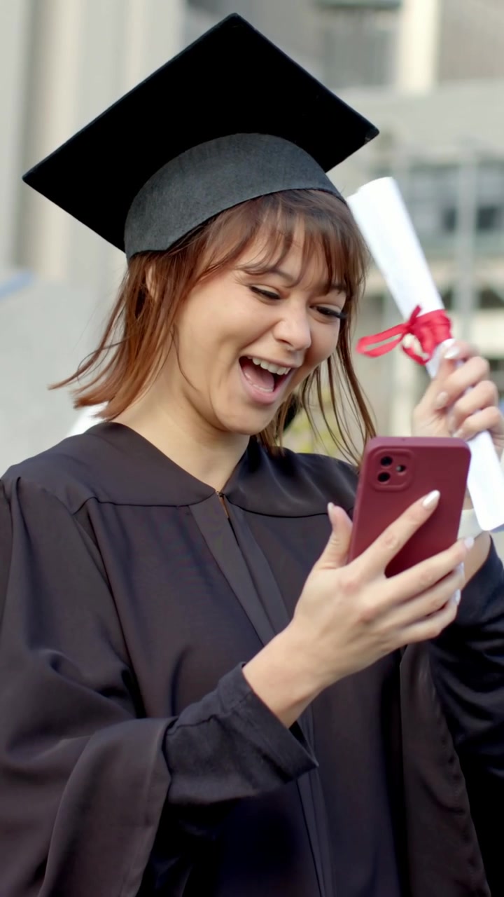 Video verticale: Che sistema la toga di laurea mentre controlla il telefono nel campus, con il diploma che appare, suscitando gioia.
