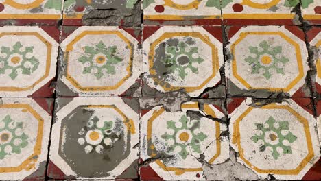 a sequence shows the gradual repair of cracked, ornate floor tiles with cement, under natural daylight, using a steady overhead camera angle
