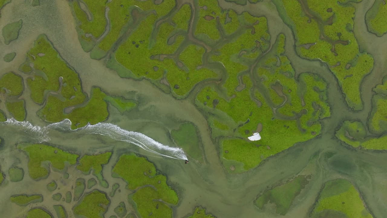 vista aérea de arriba hacia abajo de un kiteboarder en canales de paisaje de turba verde