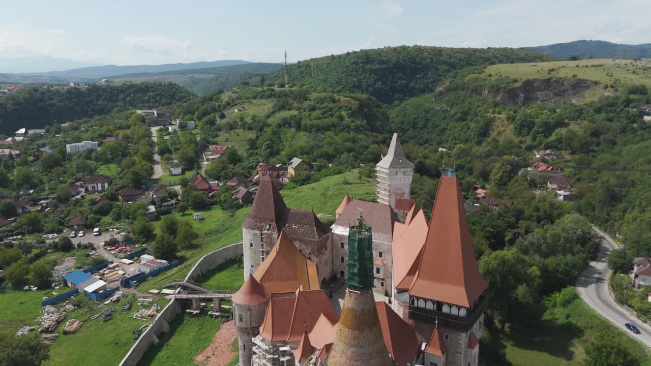 Smooth drone pullback revealing Corvin Castle and its historic surroundings, highlighting medieval architecture
