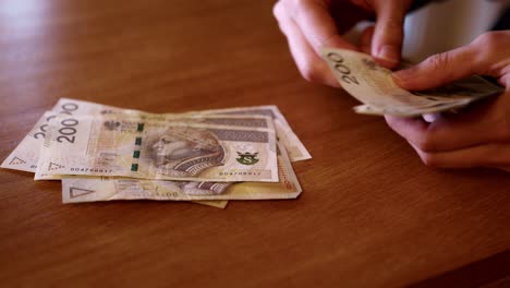 man counts money, cash polish zloty on the table