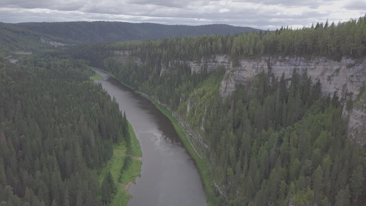 Aerial view of a river flowing through a valley with steep cliffs and lush forests