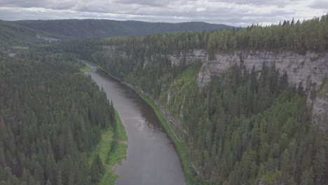 aerial view of a river flowing through a valley with steep cliffs and lush forests