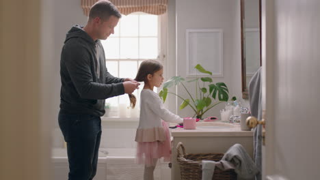 Padre-Cepillando-El-Cabello-De-Su-Hija-En-El-Baño-Linda-Niña-Preparándose-En-La-Mañana-Padre-Amoroso-Disfrutando-De-La-Paternidad-Cuidando-Al-Niño