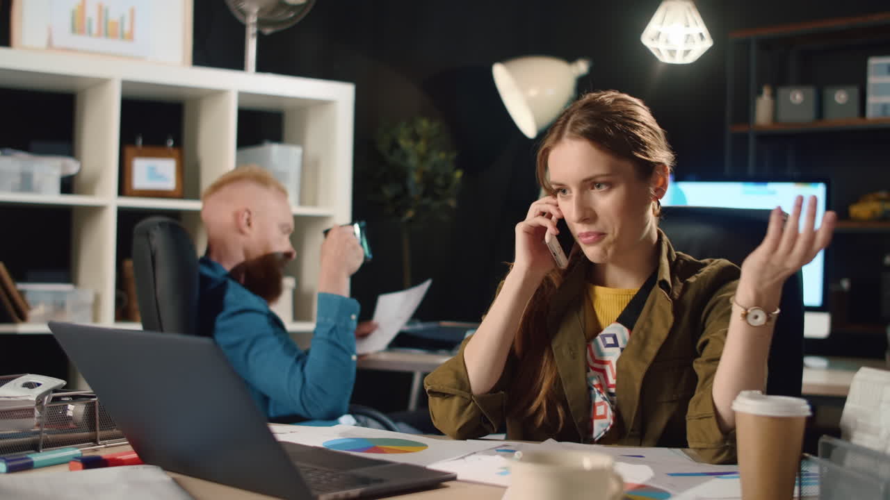 Vred kvinde taler i mobiltelefon på kontoret. Frustreret kvinde skændes indendørs