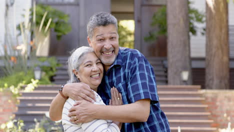 Happy-biracial-senior-couple-embracing-in-sunny-garden