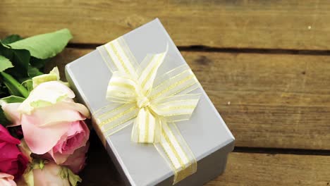 gift box with bunch of rose on wooden plank