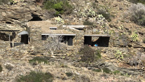 aerial view orbiting rustic stone build house on cap de creus cliffs of the national park rocky mountainside