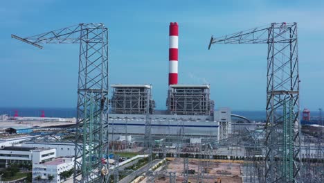 aerial drone footage of high-voltage power towers with prefabricated glass insulators to distribute electricity in an industrial park - development and industrialization concept
