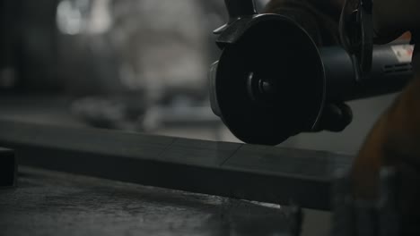 worker cuts a metal profile with a grinder in slow motion with a flying stream of sparks, metalwork in blacksmith's workshop, 4k 60p prores hq