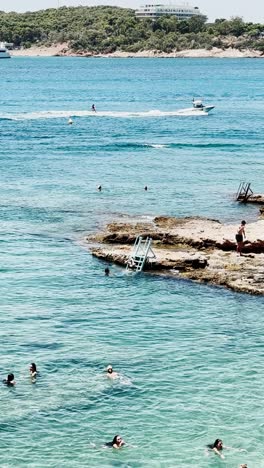 swimmers and boat trails in clear vouliagmeni lake water