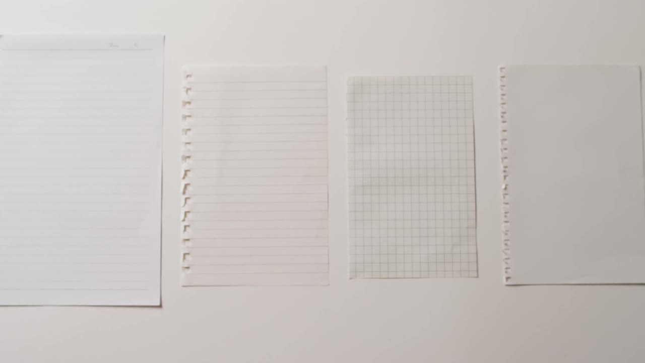 Video of close up of four sheets of notebook paper on white background