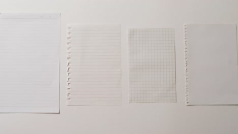 Video-of-close-up-of-four-sheets-of-notebook-paper-on-white-background