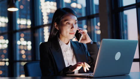 Businesswoman working late in an office, making a phone call