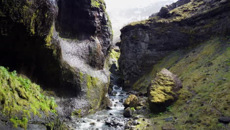 Dynamic-aerial-shot-of-a-river-in-a-canyon-then-revealing-mountains-range-in-a-distance